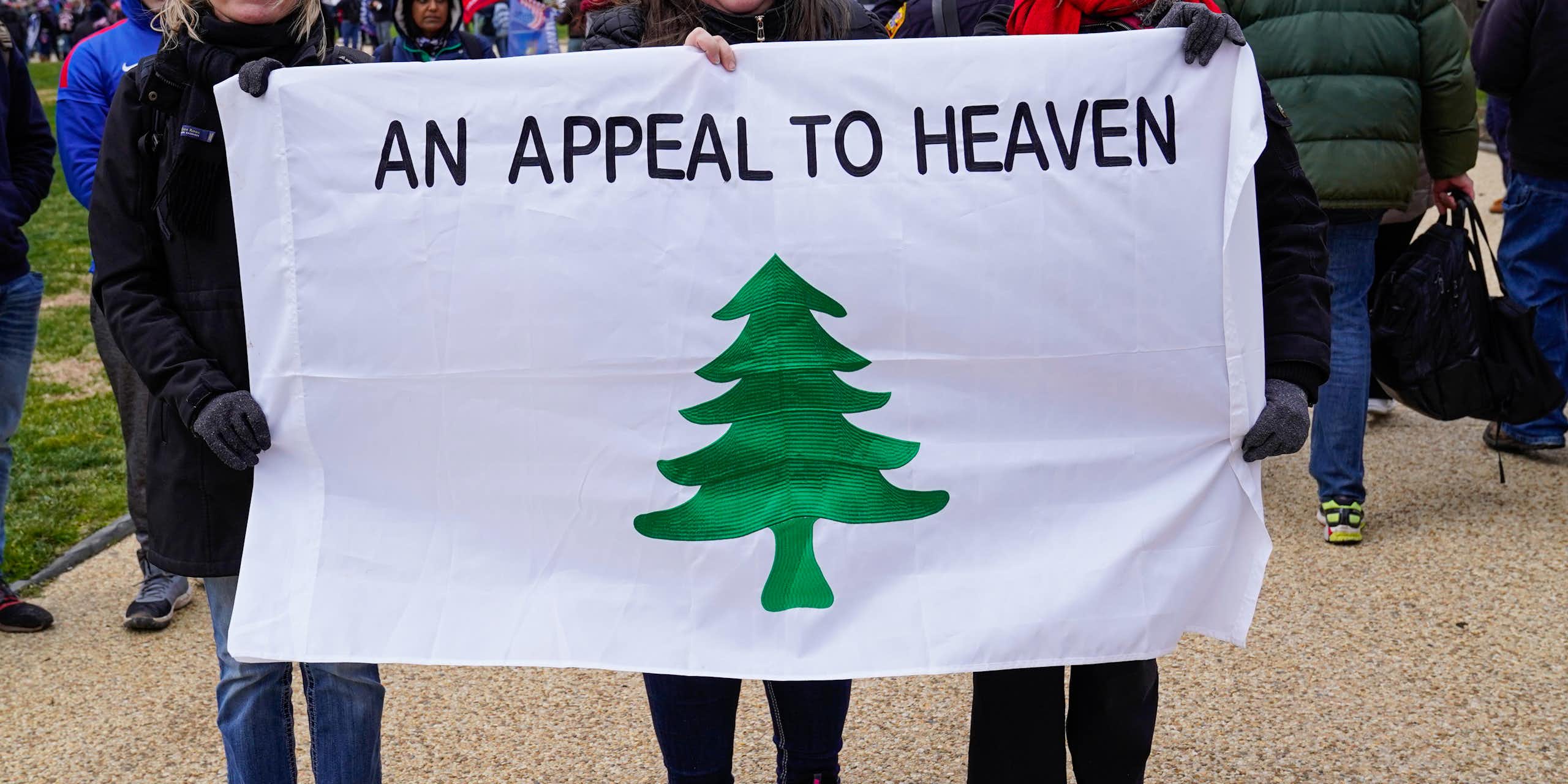 People stand holding the 'Appeal to Heaven' flag.