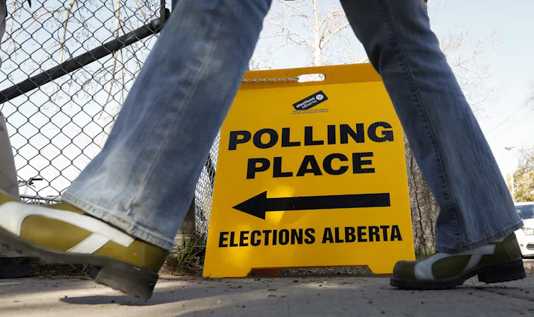A persons legs seen walking past a yellow polling lace sign.