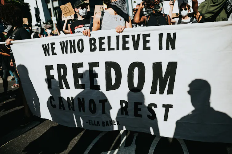 Shadows of protesters on a Black Lives Matter banner.