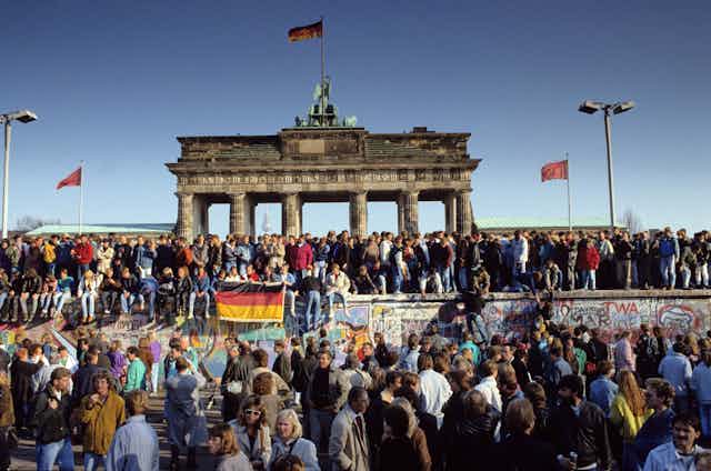 A historical photograph of people at the Berlin wall.