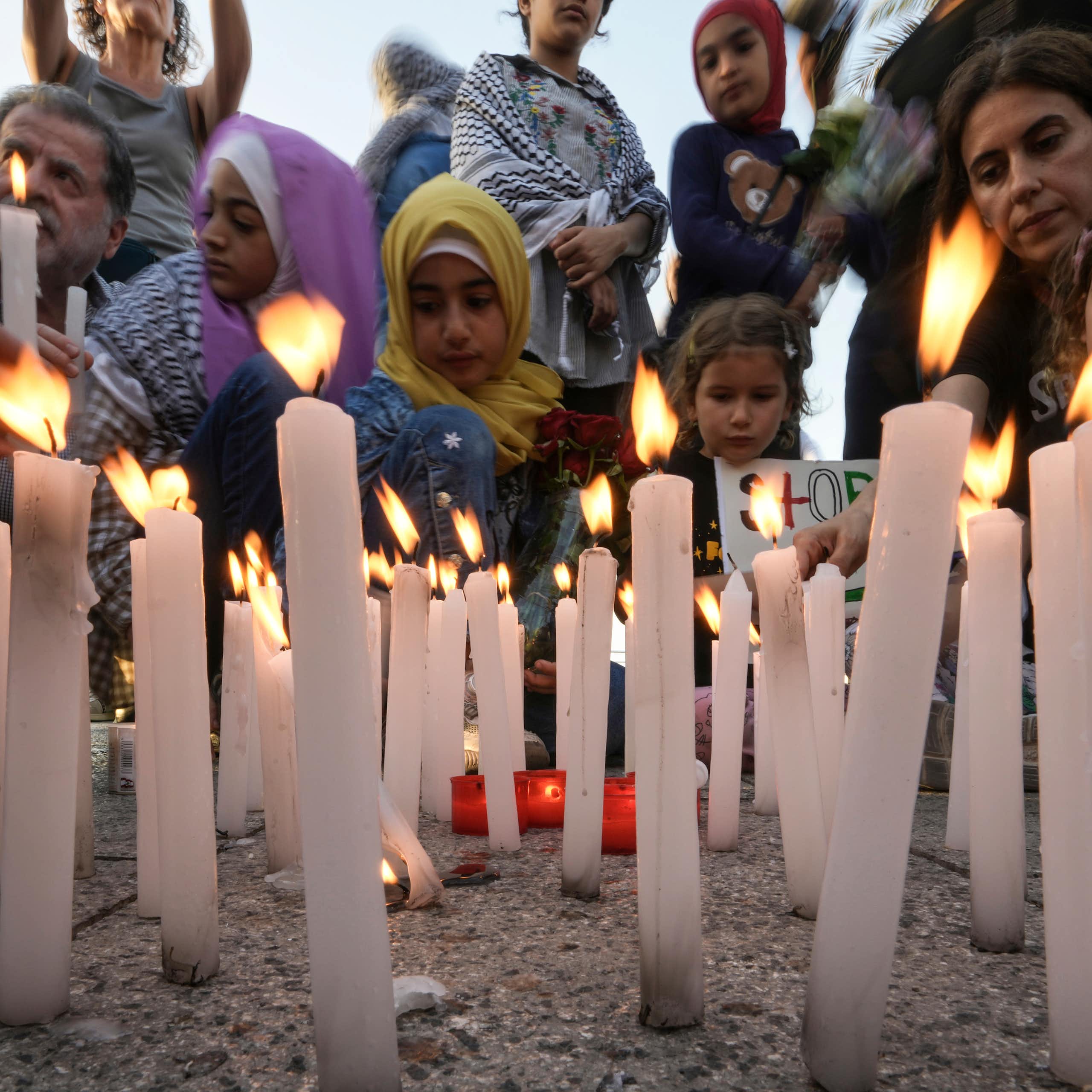 Men, women and children standing in front of lit candles.