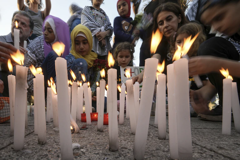 Men, women and children standing in front of lit candles.