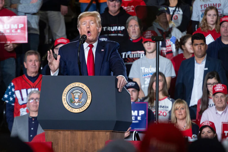 Donald Trump wearing a red tie at a lecture.