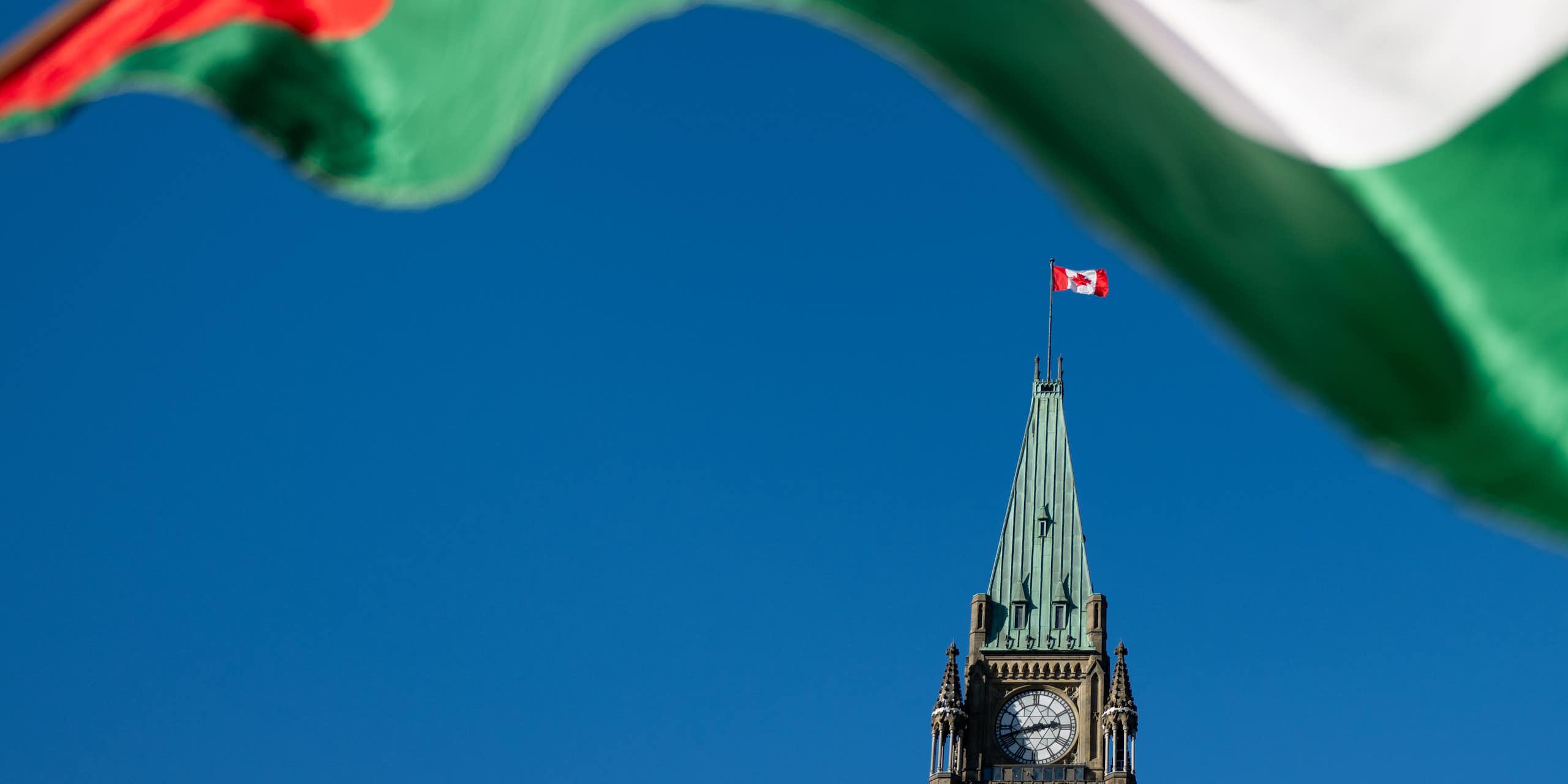 A green white and red flag frames the Peace Tower.