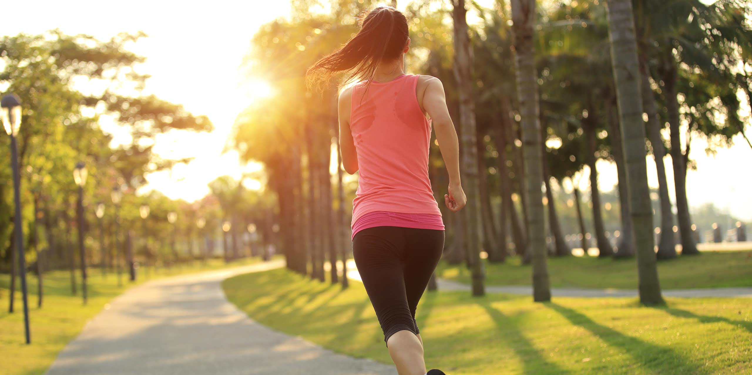 A woman goes for a run in the park at sunrise.