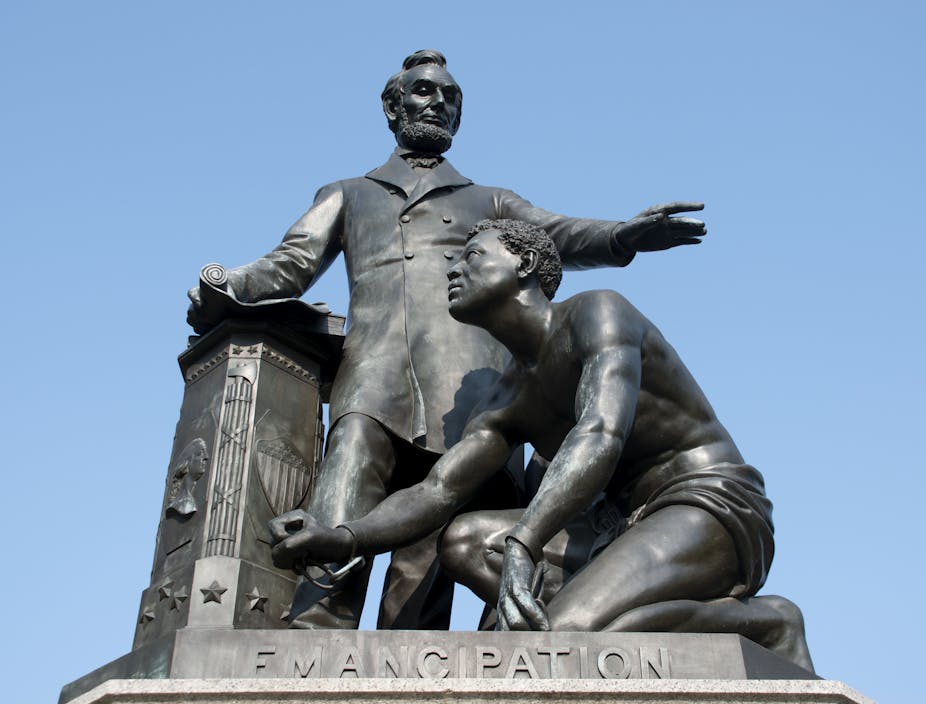 A man towering over another who is kneeling on a pedestal which has the word 'Emancipation' engraved on it.
