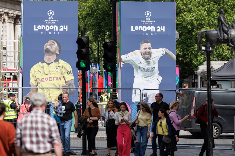 Pedestrians walk past Champions League banners in London.