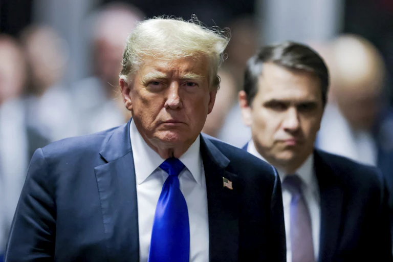 Um Donald Trump de aparência sombria olha fixamente para frente