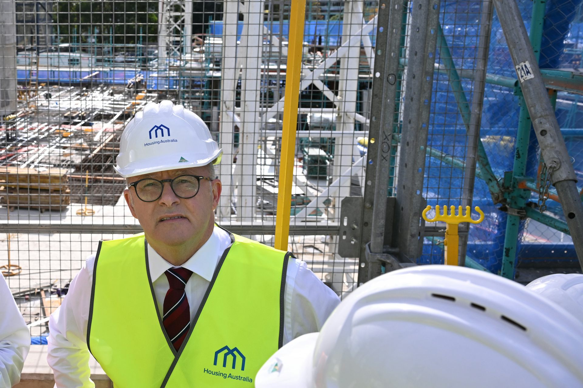 Man wearing a hard hat and high-viz vest on a housing construction site