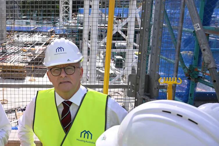 Man wearing a hard hat and high-viz vest on a housing construction site