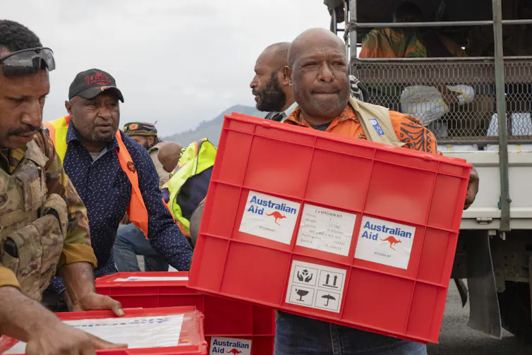 Locals unload aid from Australia on it's arrival at Wapenamanda Airport in the highlands of PNG.