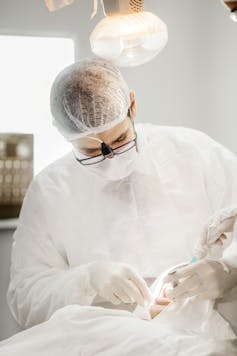 Dentist wearing hairnet works on patient