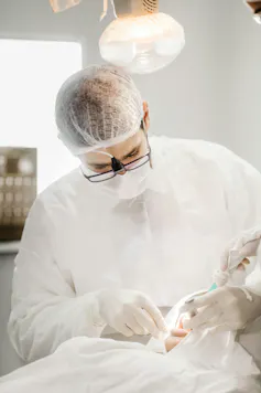 Dentist wearing hairnet works on patient