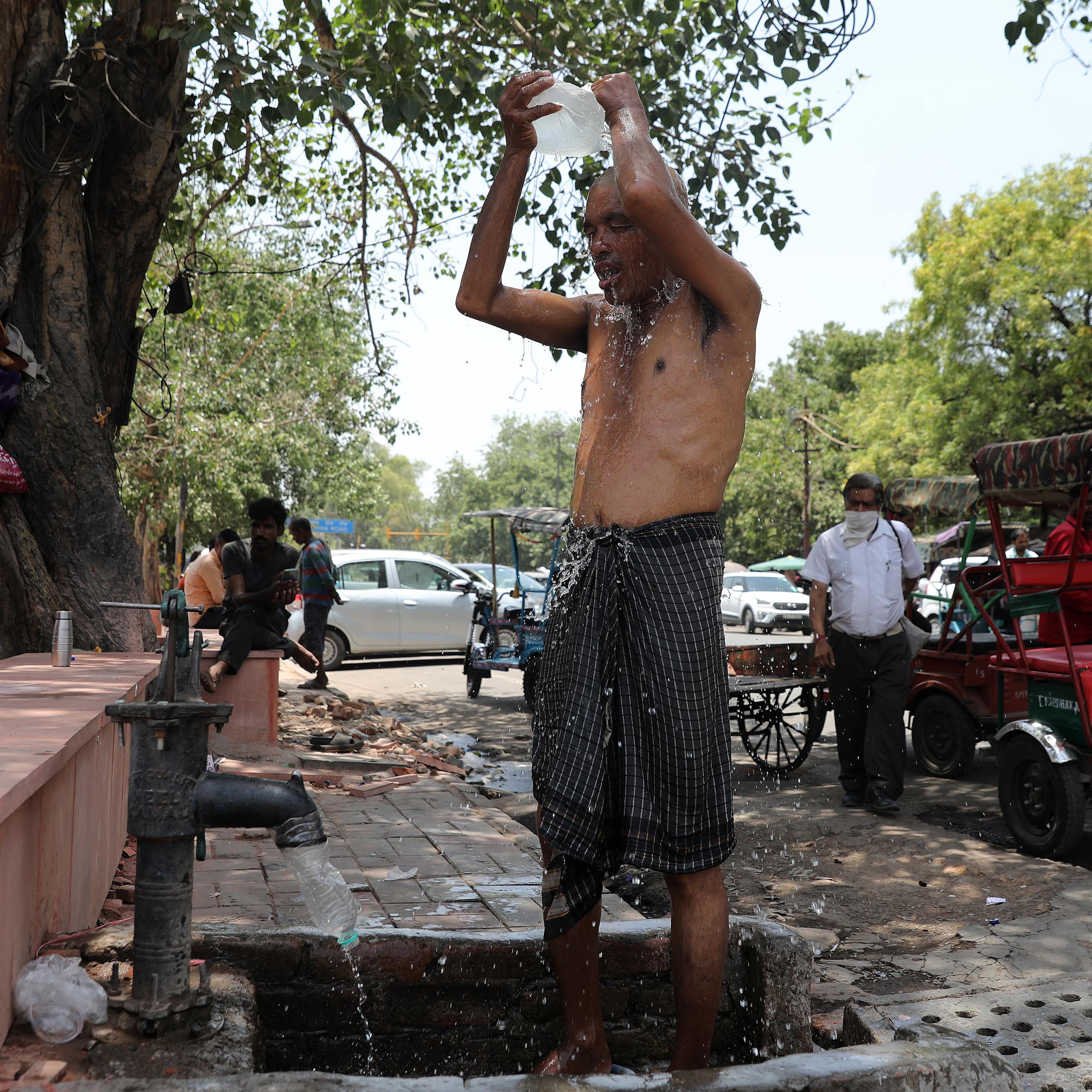 An Indian man takAn Indian man cools off with water from a handpump on the side of a street a in New Delhi, India, 30 May 2024