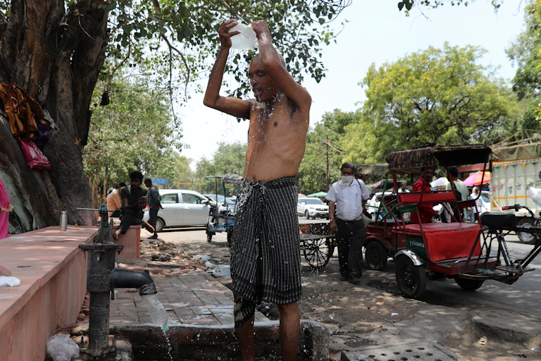 An Indian man takAn Indian man cools off with water from a handpump on the side of a street a in New Delhi, India, 30 May 2024