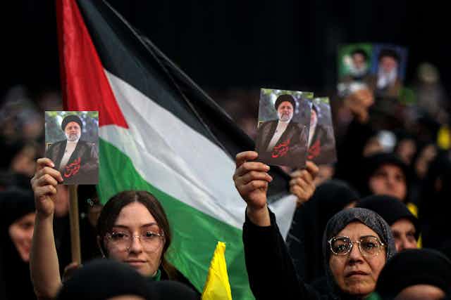 Women with photographs of Raisi behind them a flag.