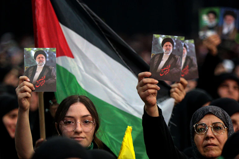 Women with photographs of Raisi behind them a flag.