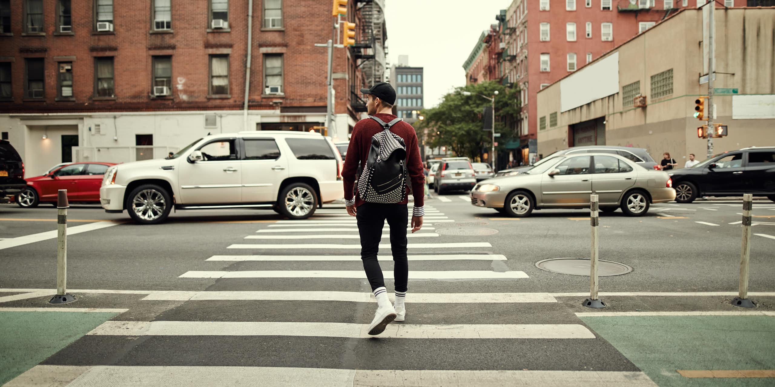 A person looks to one side while crossing a city street.