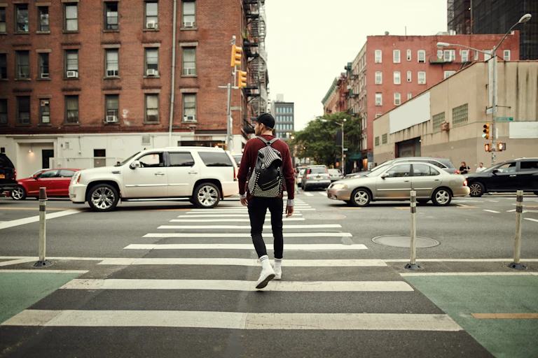 A person looks to one side while crossing a city street.