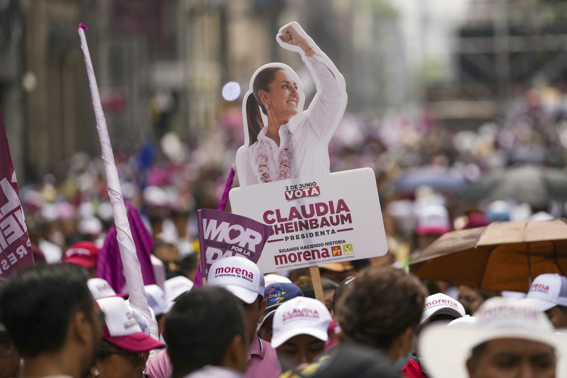 A poster of Claudia Sheinbaum, with her first raised, is seen rising above a crowd of people