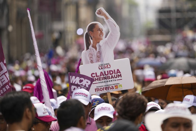 A poster of Claudia Sheinbaum, with her first raised, is seen rising above a crowd of people