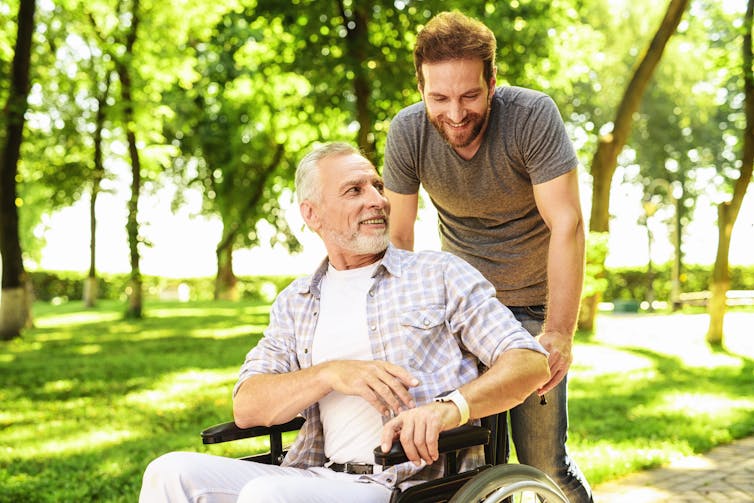 A younger man with an older man using a wheelchair.