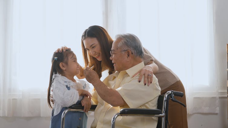 A woman with a young child and older man using a wheelchair