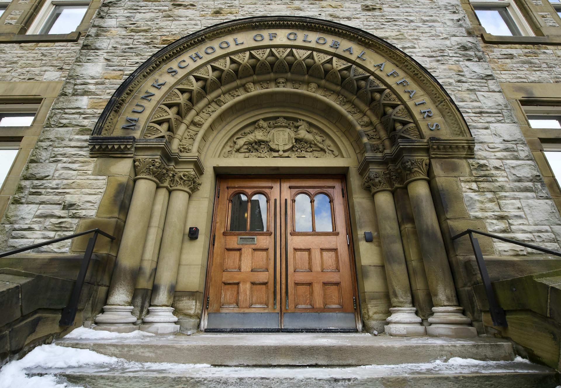 A curved stone archway over a large wooden store reads the Munk School of Global Affairs.