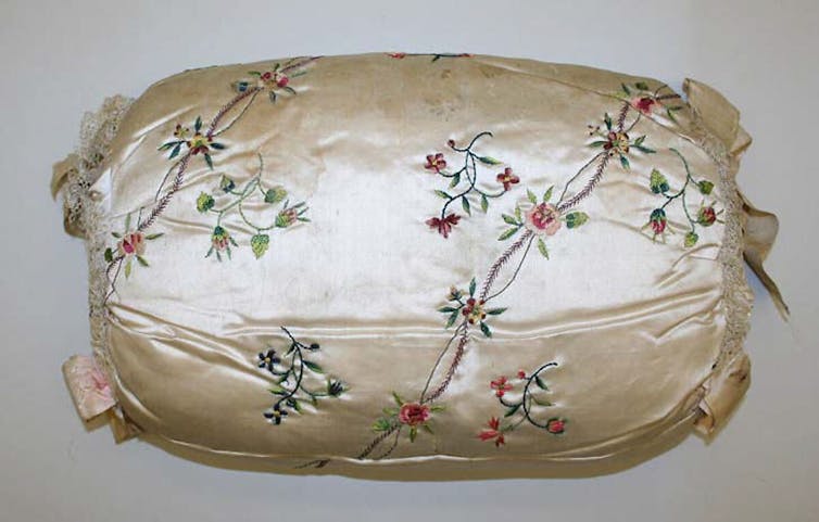 A light pink silk muff with floral embroidery.