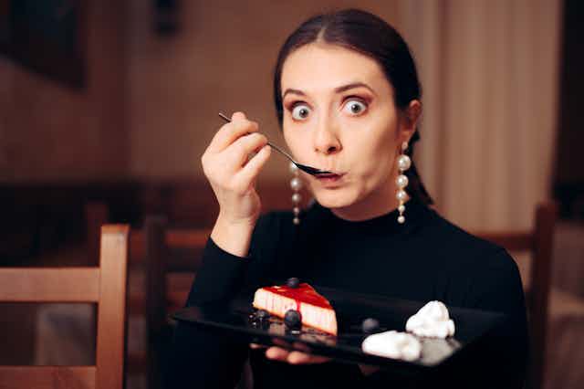 Woman with guilty expression eating cheesecake