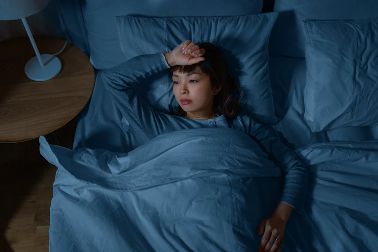 Woman awake in bed, hand on forehead