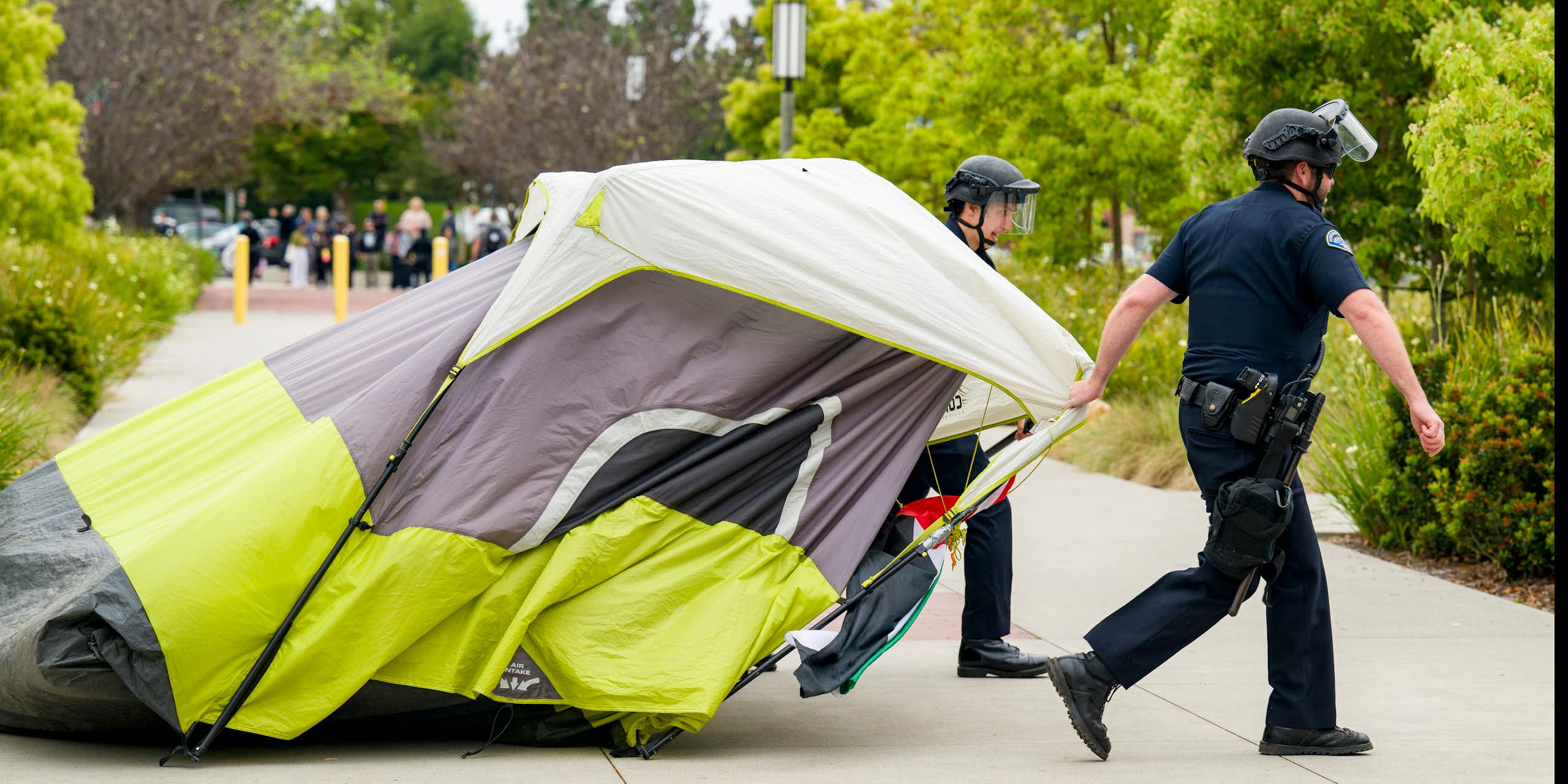 Two police officers drag a tent.