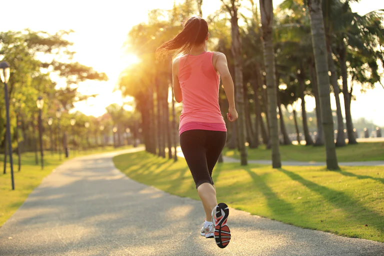 Una mujer sale a correr por el parque al amanecer.