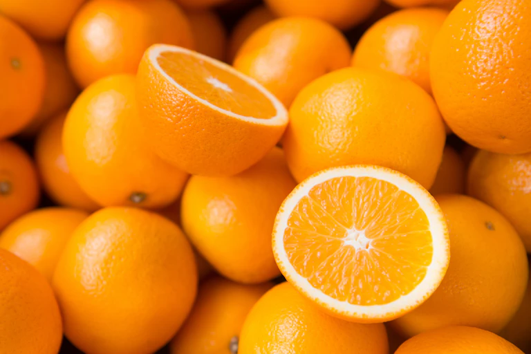 Sliced orange on top of pile of oranges