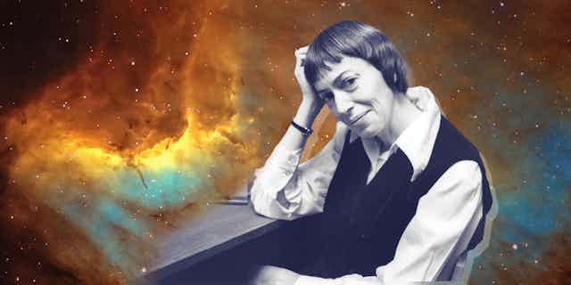 Ursula K. Le Guin in a chair, the background is a photo of space