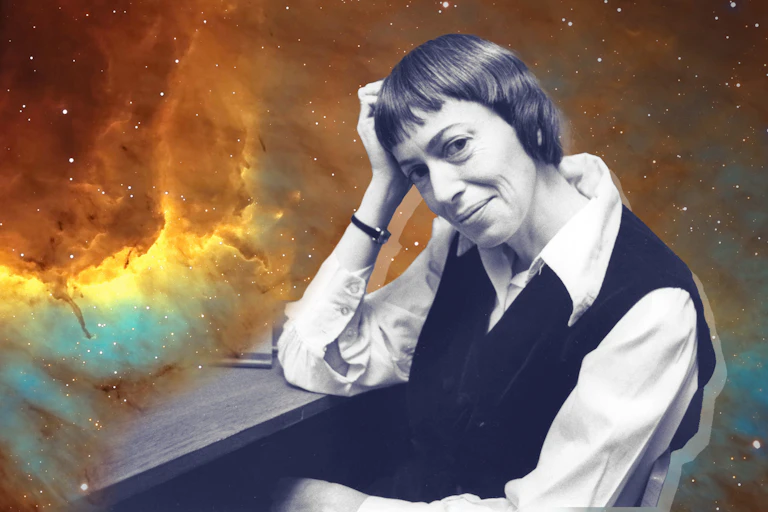 Ursula K. Le Guin in a chair, the background is a photo of space