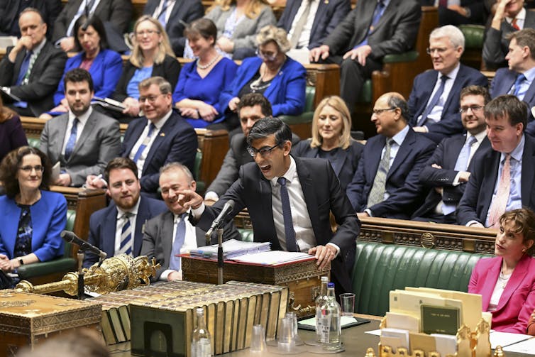 Rishi Sunak at the dispatch box in the house of commons, pointing emphatically towards Starmer, who is out of frame, while MPs around Sunak on green benches laugh in support