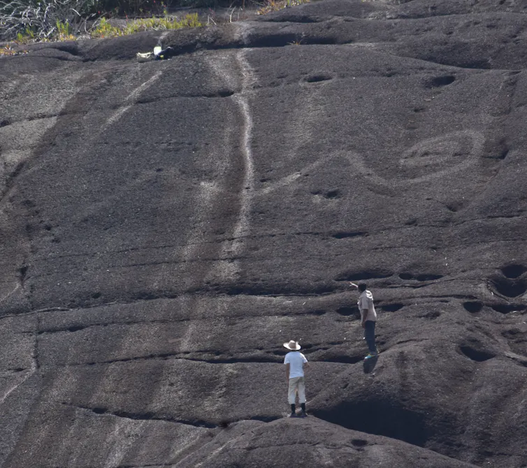 Telephoto shot of monumental rock art of snake tail in Colombia, humans for scale.