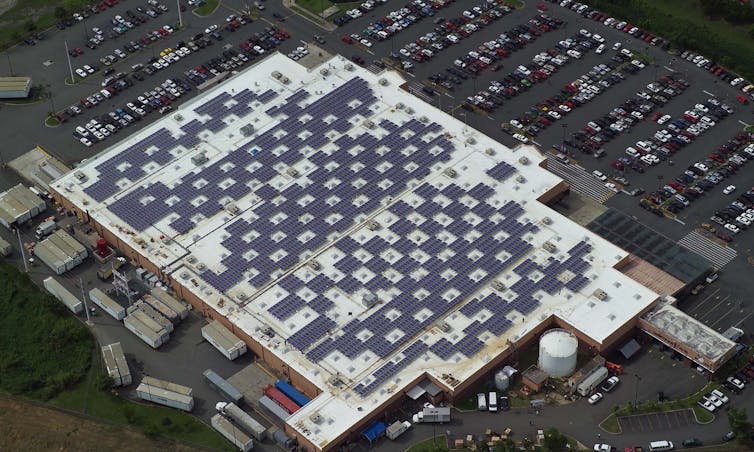 Aerial view of a big-box store roof covered with solar PV panels.