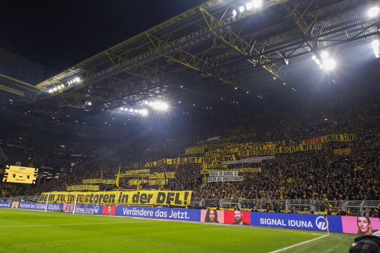 Dortmund supporters protest with yellow banners against private investment in German football.