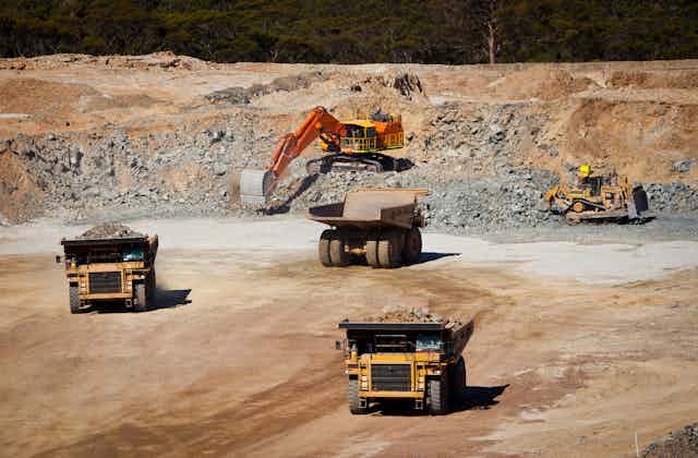 Trucks at an open cast mine with digger in background
