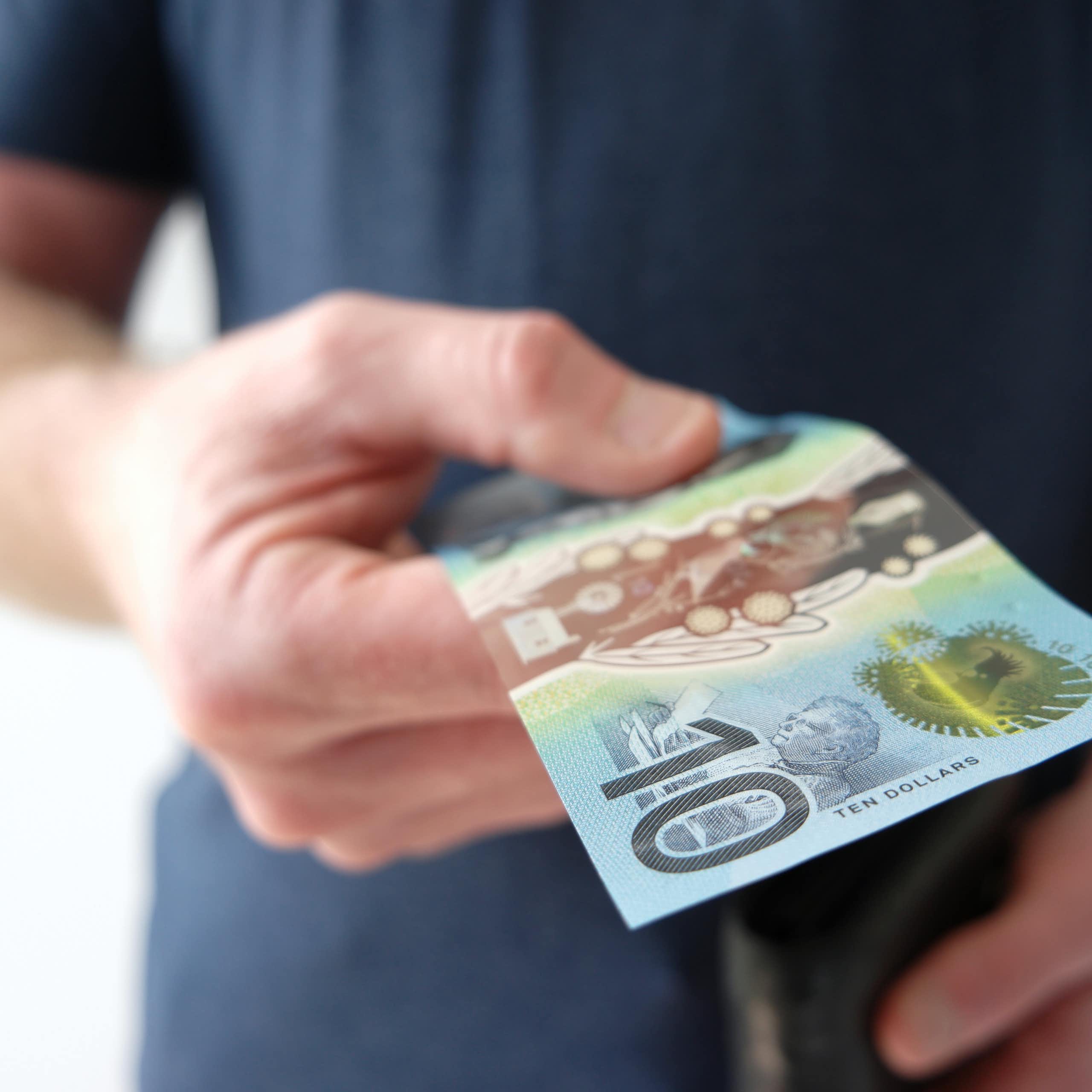 Man handing out ten dollar Australian note