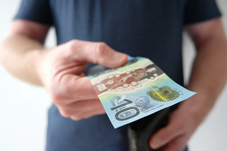 Man handing out ten dollar Australian note