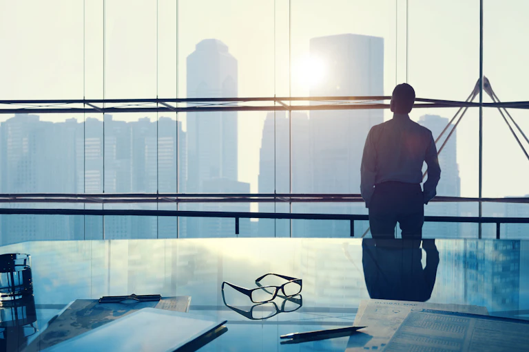 Man in office looking out window to city skyline
