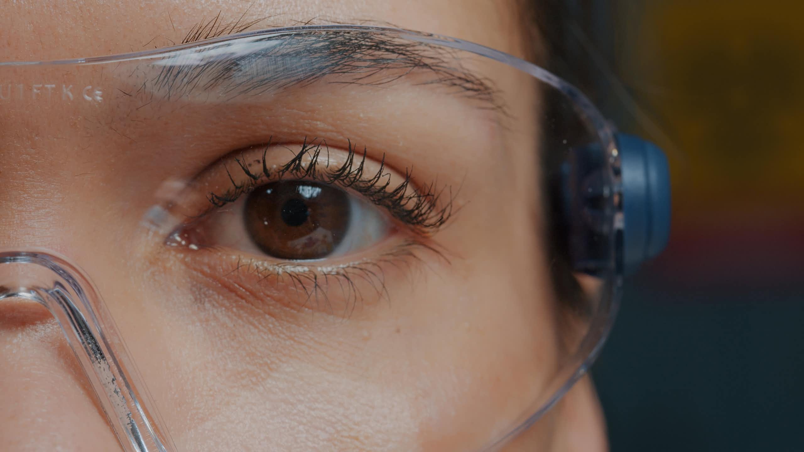 Photo of a woman's eye behind safety goggles.