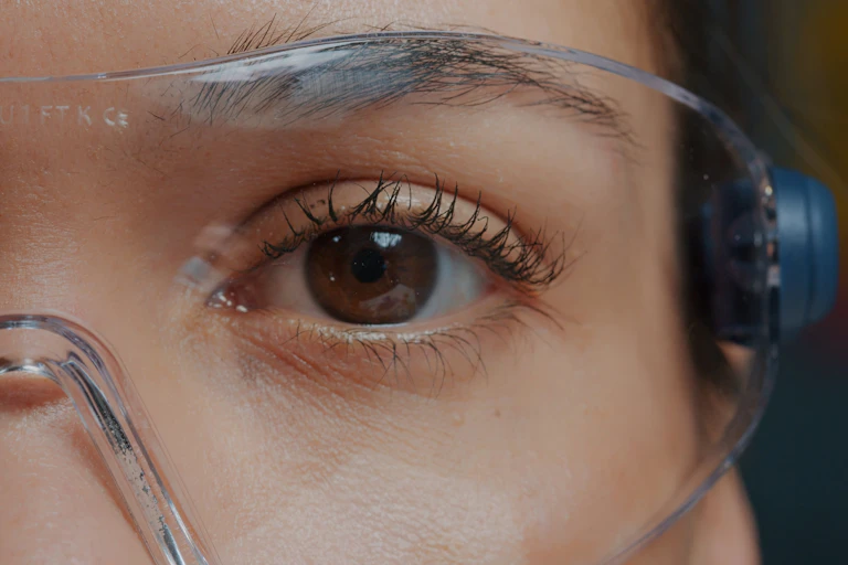 Photo of a woman's eye behind safety goggles.