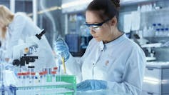 Woman scientist using a dropper to put fluid in a test tube