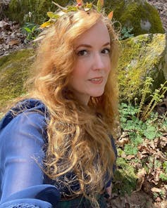 Instagram user gracesidhe sitting next to a mossy rock with a flower crown on her head