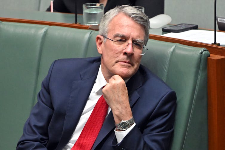 A man in a suit strokes his chin