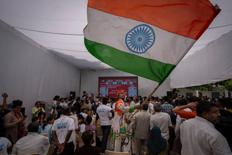 Supporters of the India Congress Party wave flags as they watch the election count, Jue 2024.